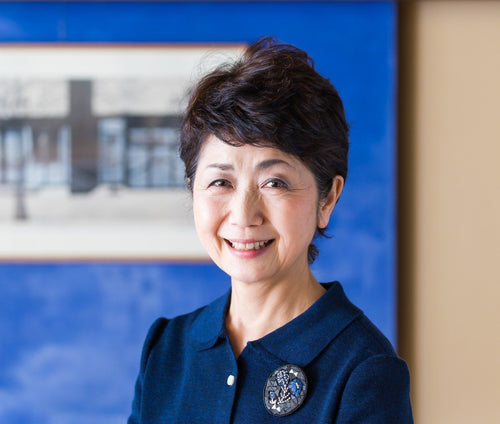 Portrait of Vice-President Miyako Watanabe of Ippodo against bright blue background with blurred photograph
