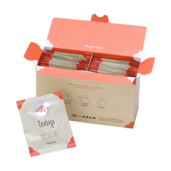 Open box filled with Ippodo hojicha tea bag packets with orange accents, alongside a single hojicha packet in front.