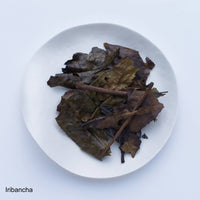 Deep brown roasted bancha green tea leaves and stems from Kyoto on white plate on white table