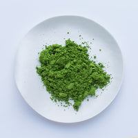 Bright green loose Japanese Ippodo Tea Kan matcha powder on white plate on white table