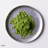 Loose green finely ground premium verdant green Japanese Ippodo Kuon Matcha tea powder on silver plate on white table