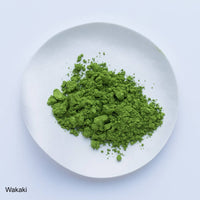Bright green loose Japanese Ippodo Tea Wakaki matcha powder on white plate on white table
