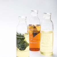 Three engraved Ippodo Tea glass carafes filled with different teas including two with one-pot teabags steeping for cold brew
