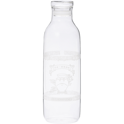 A clear glass bottle with a narrow neck and wide body. It appears empty and has some etched or printed design on its surface, though the details aren't clearly visible. The bottle has a simple, cylindrical shape typical of water or juice bottles, with a slight lip at the top where a cap would typically be placed. The glass is transparent and clean.