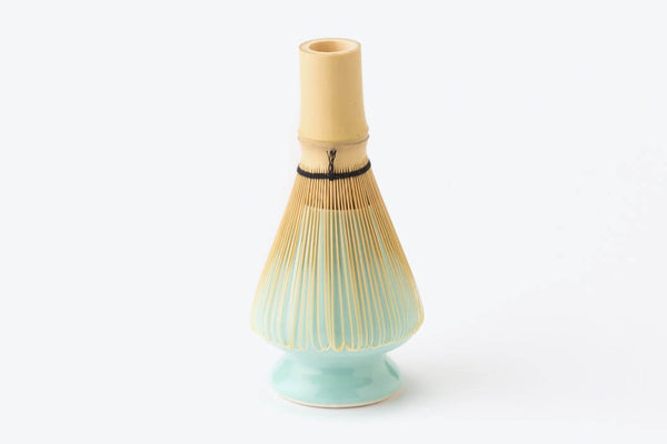 Light pastel turquoise blue Ippodo Tea ceramic stand supporting bamboo Chasen 80-tip matcha whisk with black ribbon