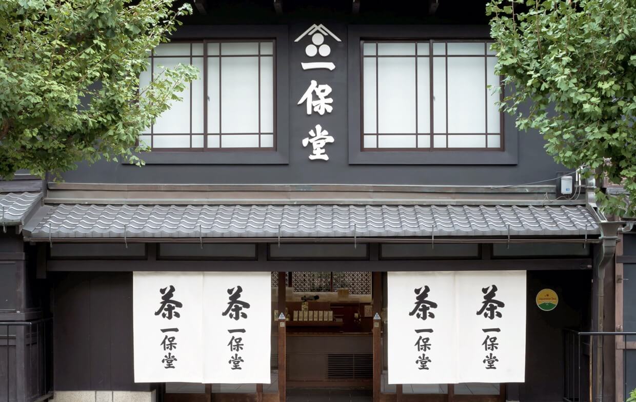 Black storefront of Ippodo Tea's flagship store, tearoom and headquarters in Kyoto, Japan with lush cherry blossom trees