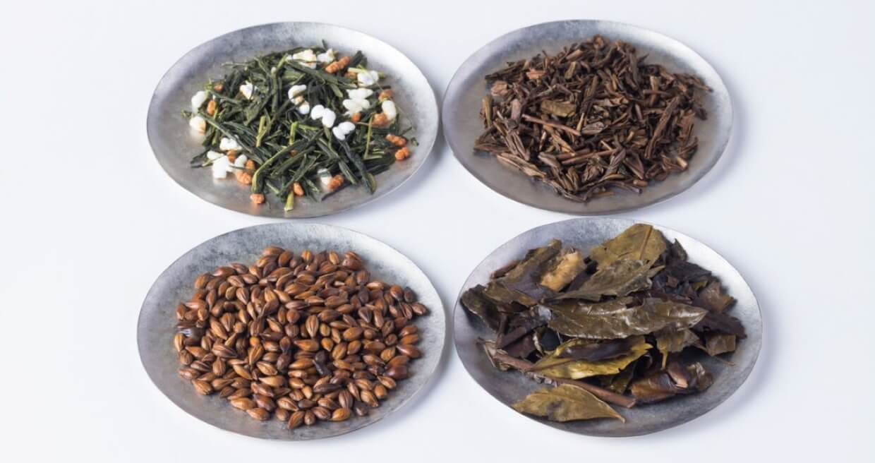 Comparison of different bancha loose leaf teas on plates. Genmaicha, hojicha, mugicha, and iribancha