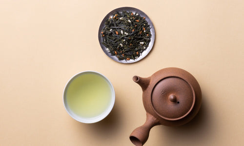 Small plate with sample of Ippodo Obukucha tea with roasted rice beside teacup of brewed tea and brown clay Yakishimi kyusu