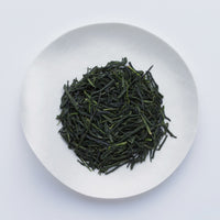 White plate of dark green prized high-grade loose leaf Ippodo Tea Kanro gyokuro tea leaves on white table
