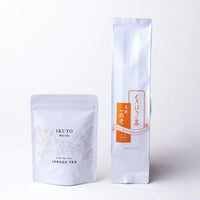 White resealable bag of Ikuyo matcha with floral design beside white and orange package of Stems Hojicha by Ippodo Tea