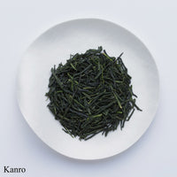 White plate of dark green high-grade loose leaf Ippodo Tea gyokuro tea leaves on white table labeled Kanro