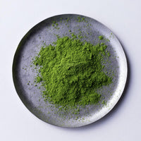 Green loose New Harvest Matcha powder on silver artisan made plate against white backdrop