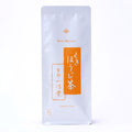 A tall white pouch of Ippodo Tea Stems Hojicha (80g / 2.82 oz) with an orange vertical banner with Japanese calligraphic text for "Kuki Hojicha". - thumbnail 2