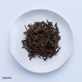Sample of Ippodo Hojicha roasted green tea leaves and stems on white plate, on white table