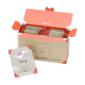 Open box filled with Ippodo hojicha tea bag packets with orange accents, alongside a single hojicha packet in front. - thumbnail 1
