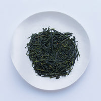 White plate of dark green most popular loose leaf Ippodo Tea Hosen Sencha Japanese tea leaves on white table