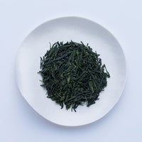 White plate of dark green prized high-grade loose leaf Ippodo Tea Ippoen gyokuro tea leaves on white table
