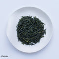White plate of dark green dried premium loose leaf Japanese Kaboku Sencha tea leaves by Ippodo Tea Co. on white table