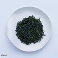 White plate of dark green prized high-grade loose leaf Ippodo Tea Kanro gyokuro tea leaves on white table