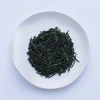 White plate of dark green prized high-grade loose leaf Ippodo Tea Kanro gyokuro tea leaves on white table