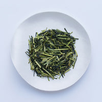 Ippodo Tea Stems Sencha sample depicting light and dark green loose stems on white plate 