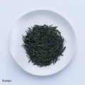 White plate of dark green dried premium loose leaf Japanese Kumpu Sencha tea leaves by Ippodo Tea Co. on white table