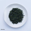 Loose leaf dark green rolled dried Ippodo Mantoku Gyokuro light refreshing Japanese green tea on white plate on white table