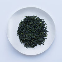 Loose leaf dark green rolled dried Ippodo Mantoku Gyokuro light refreshing Japanese green tea on white plate on white table