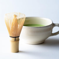 Korean artisan-made Chasen 80-tip bamboo matcha whisk tea utensil with green matcha tea in ceramic tea cup