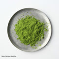 Green loose New Harvest Matcha powder on silver artisan made plate against white backdrop