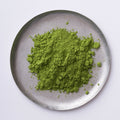 Green loose New Harvest Matcha powder on silver artisan made plate against white backdrop
