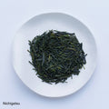 White plate of dark green dried refreshing loose leaf Japanese Nichigetsu Sencha tea leaves by Ippodo Tea on white table