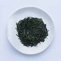 White plate of dark green dried refreshing loose leaf Japanese Nichigetsu Sencha tea leaves by Ippodo Tea on white table
