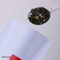 Stainless steel tablespoon measure of genmaicha green tea mixed with roasted rice scooped from red and white bag of Obukucha