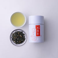 Can of Ippodo Tea Obukucha beside porcelain teacup of brewed Good Fortune tea and plate of loose green tea and roasted rice