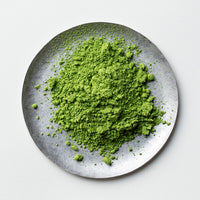Loose green finely ground milled Japanese Ippodo Premium Select Matcha tea powder on silver plate on white table