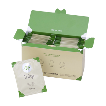 Open box filled with Ippodo sencha tea bag packets with green accents, alongside a single sencha packet in front.