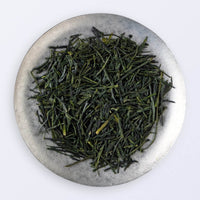 Ippodo Tea Uji Shincha sample depicting loose green needle-like rolled futsumushi tea leaves on silver plate on white table