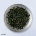 Ippodo Tea Uji Shincha sample depicting loose green needle-like rolled futsumushi tea leaves on silver plate on white table