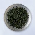 Ippodo Tea Uji Shincha sample depicting loose green needle-like rolled futsumushi tea leaves on silver plate on white table