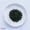 Loose leaf darker green rolled dried Ippodo Tenka-Ichi Gyokuro premium Japanese green tea on white plate on white table