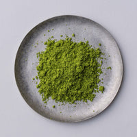 Bright green loose Japanese Ippodo Tea Tsukikage matcha powder on grey plate on white table