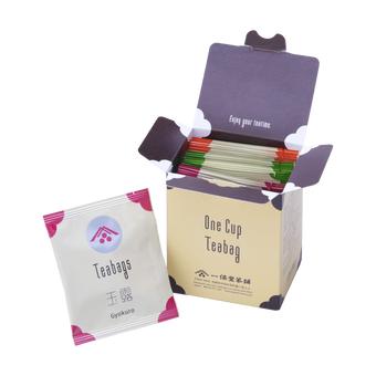 Open box of Ippodo One Cup Teabag packets with an individual gyokuro tea bag packet in front on a white background.
