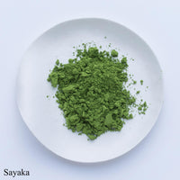 Vibrant green loose stone ground Sayaka Japanese matcha powder by Ippodo Tea on white plate on white table