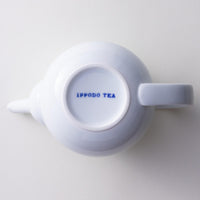 Bottom view of snow white glazed porcelain symmetrical Japanese Hasami-yaki kyusu teapot showing "Ippodo Tea" in blue writing