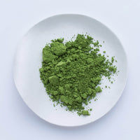 Bright green loose Japanese Ippodo Tea Ikuyo matcha powder on white plate on white table