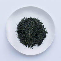 White plate of dark green prized high-grade loose leaf Ippodo Tea Ippoen gyokuro tea leaves on white table