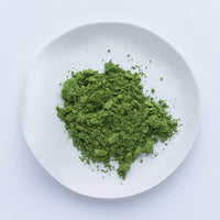Bright green loose Japanese Ippodo Tea Kan matcha powder on white plate on white table