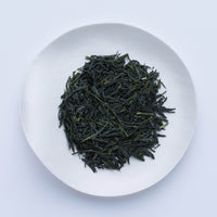 Loose leaf dark green rolled dried Ippodo Mantoku Gyokuro light refreshing Japanese green tea on white plate on white table