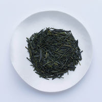 White plate of dark green dried refreshing loose leaf Japanese Nichigetsu Sencha tea leaves by Ippodo Tea Co. on white table